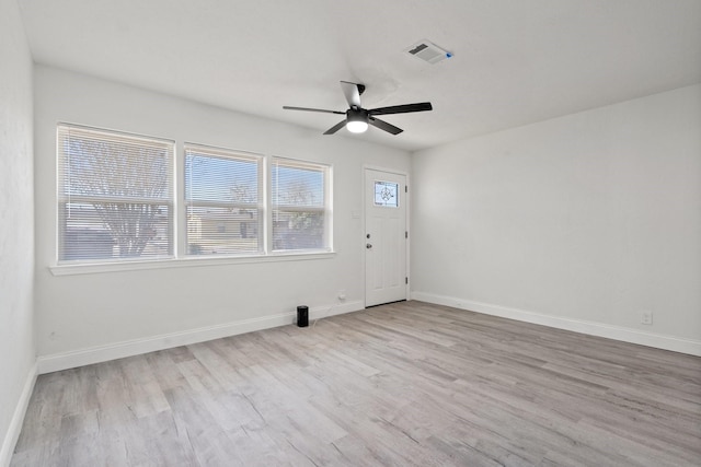 empty room featuring baseboards, a ceiling fan, visible vents, and light wood-style floors