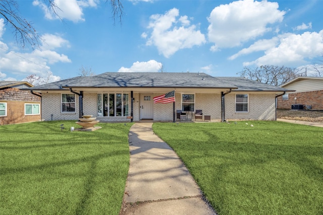 ranch-style home with brick siding, a front lawn, and roof with shingles