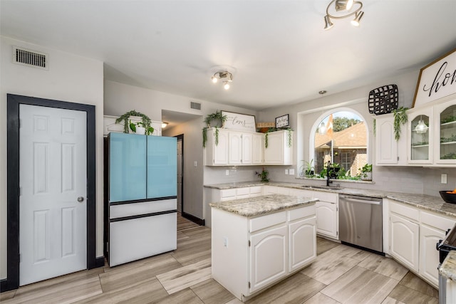 kitchen with dishwasher, a kitchen island, visible vents, and white cabinets