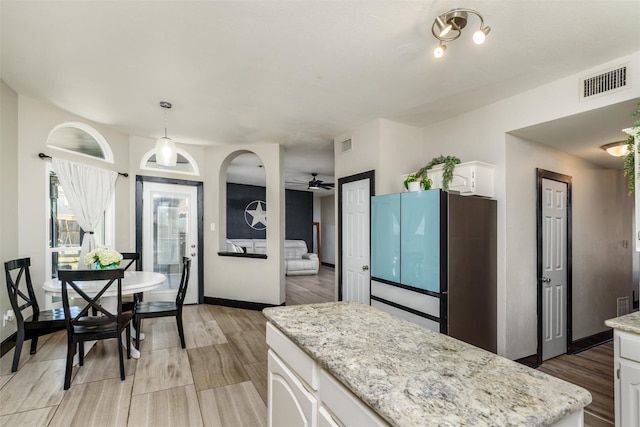 kitchen featuring light wood-type flooring, visible vents, white cabinets, and freestanding refrigerator