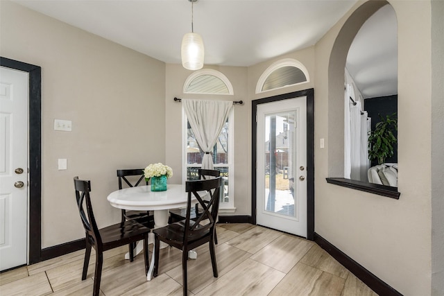 dining room with arched walkways, wood finish floors, and baseboards