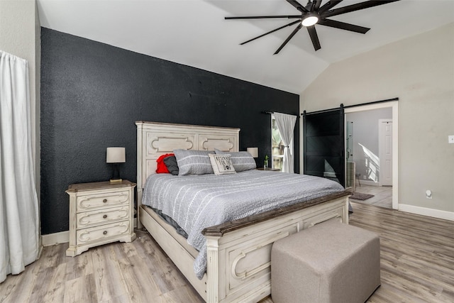 bedroom featuring lofted ceiling, a barn door, a ceiling fan, baseboards, and light wood-style floors