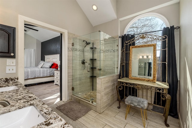 ensuite bathroom with ensuite bathroom, wood finish floors, a sink, vaulted ceiling, and a stall shower