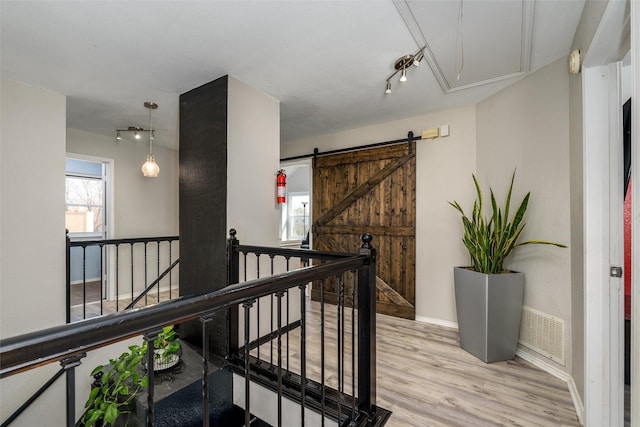 hall featuring attic access, a wealth of natural light, light wood-style flooring, and an upstairs landing