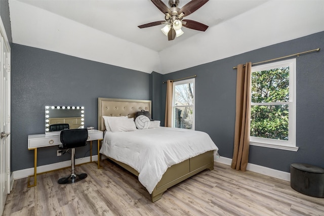 bedroom with light wood-style floors, lofted ceiling, ceiling fan, and baseboards