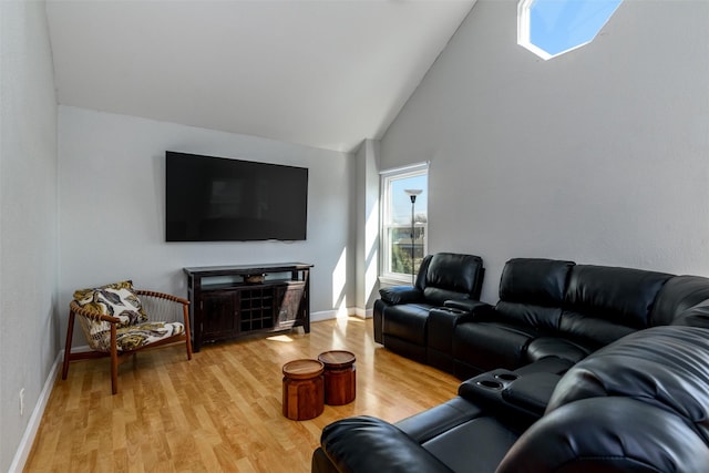 living room featuring high vaulted ceiling, light wood-style flooring, and baseboards