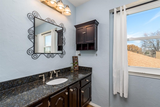 bathroom with a textured wall, baseboards, and vanity