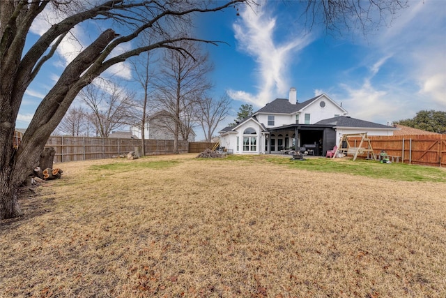 back of property with a yard, a chimney, a patio, and a fenced backyard