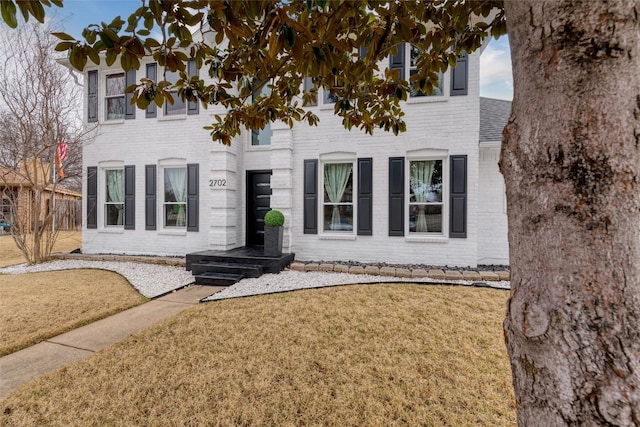 view of front facade with brick siding and a front lawn