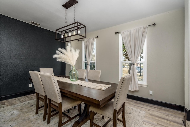 dining area featuring light wood-style floors, visible vents, a notable chandelier, and baseboards