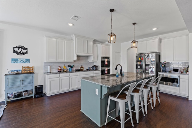 kitchen featuring backsplash, dark wood finished floors, a sink, a breakfast bar, and stainless steel appliances