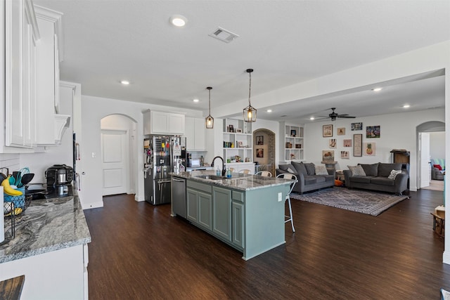 kitchen with a ceiling fan, arched walkways, a sink, dark wood-style floors, and stainless steel appliances