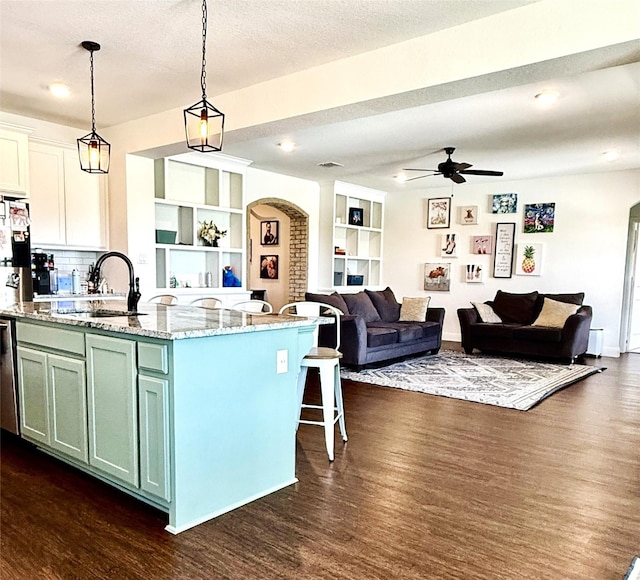 kitchen featuring a sink, arched walkways, ceiling fan, and dark wood-type flooring