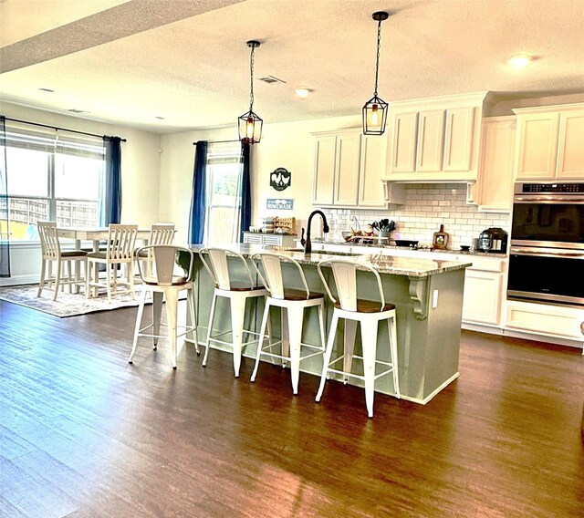 kitchen with double oven, a sink, a textured ceiling, and a healthy amount of sunlight