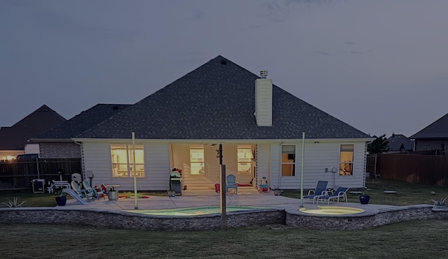 back of house with a patio, a fenced backyard, a chimney, a lawn, and a hot tub