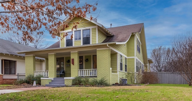 view of front of property with covered porch, a front lawn, cooling unit, and brick siding