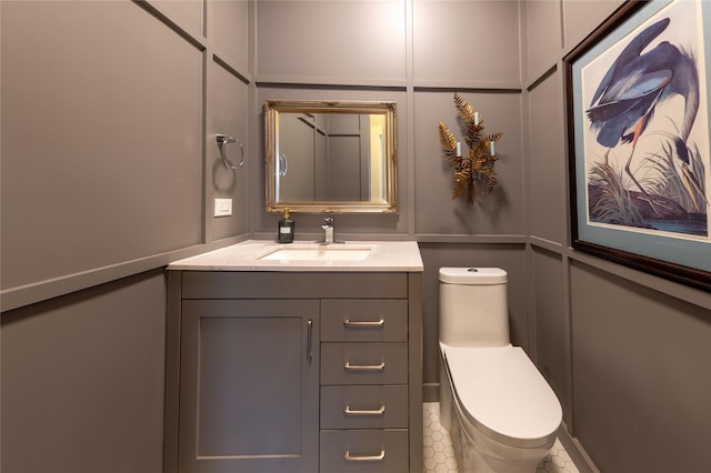 bathroom with toilet, a decorative wall, and vanity