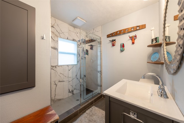 bathroom featuring a marble finish shower, a textured ceiling, and vanity