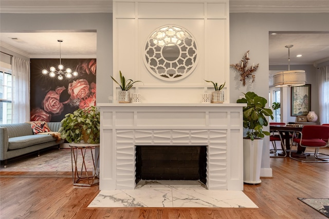 interior details featuring ornamental molding, a chandelier, a fireplace, and wood finished floors