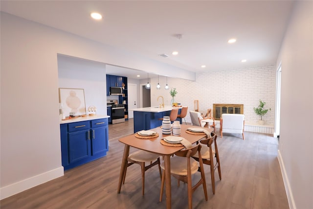 dining room featuring dark wood-style floors, brick wall, and baseboards