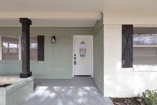 entrance to property with covered porch and brick siding