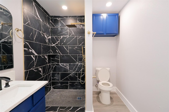 full bathroom with tiled shower, vanity, toilet, and baseboards