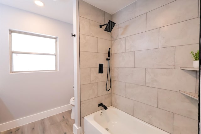 bathroom with toilet, baseboards, wood finished floors, and shower / bathtub combination