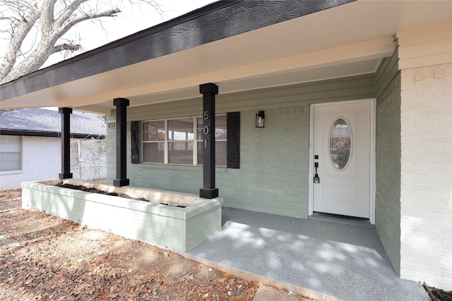 entrance to property featuring covered porch and brick siding