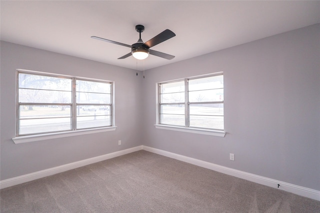 carpeted empty room with a ceiling fan and baseboards