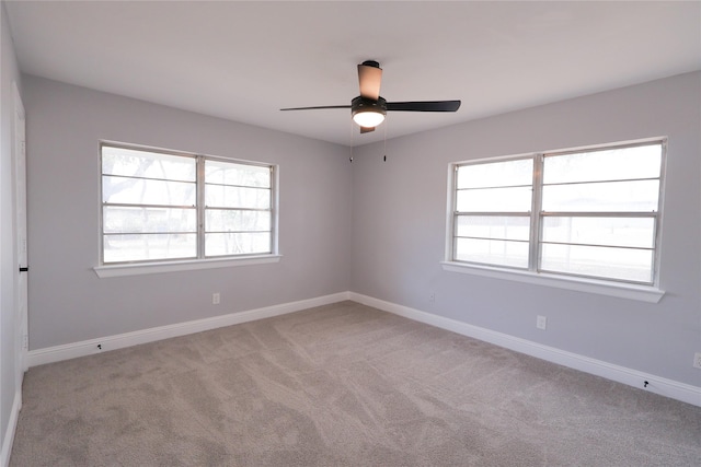 spare room featuring light carpet, a ceiling fan, and baseboards