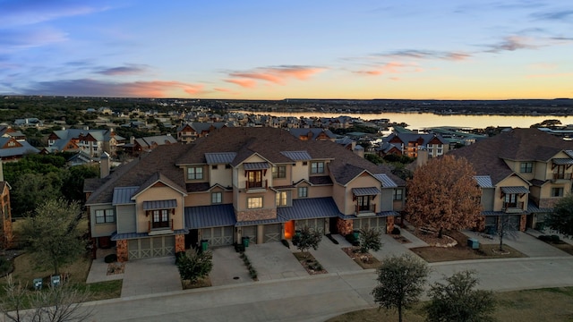 view of front facade featuring a water view, a residential view, concrete driveway, and stucco siding