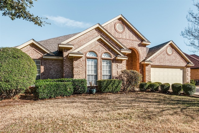 view of front of property with brick siding, a front lawn, an attached garage, and a shingled roof