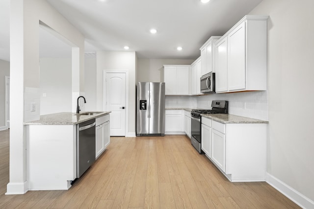 kitchen featuring white cabinetry, appliances with stainless steel finishes, light stone counters, and a sink