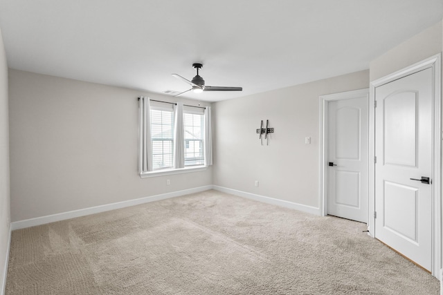 unfurnished room with light carpet, visible vents, a ceiling fan, and baseboards