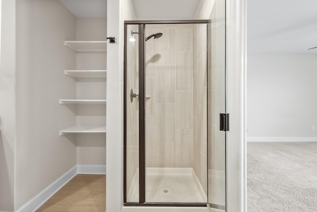 bathroom with a stall shower, wood finished floors, and baseboards