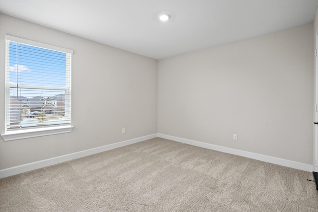 unfurnished room with light colored carpet and baseboards