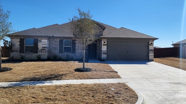 ranch-style home featuring a garage, fence, driveway, stone siding, and roof with shingles