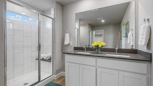 bathroom with double vanity, wood finished floors, a sink, and visible vents