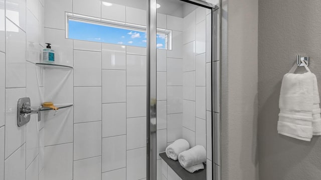 bathroom with a textured wall and a tile shower