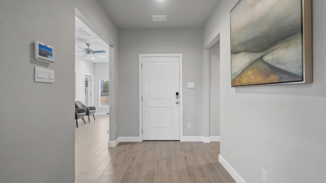 corridor with visible vents, light wood-style flooring, and baseboards