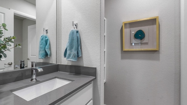 bathroom featuring a textured wall and vanity