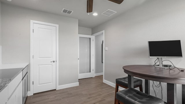 office featuring baseboards, visible vents, ceiling fan, and light wood finished floors