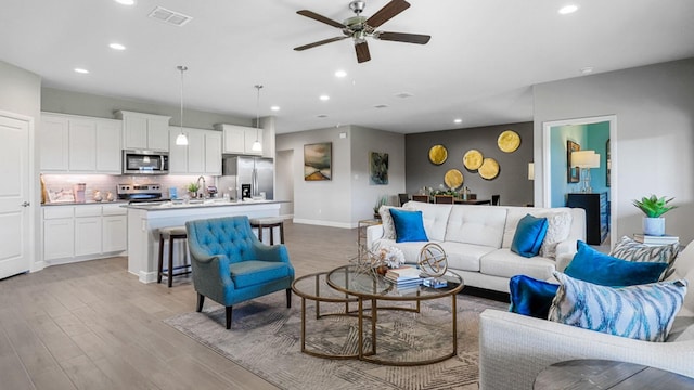 living room with light wood finished floors, visible vents, baseboards, ceiling fan, and recessed lighting