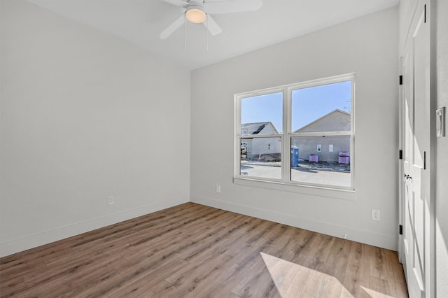 spare room with a ceiling fan, light wood-type flooring, and baseboards