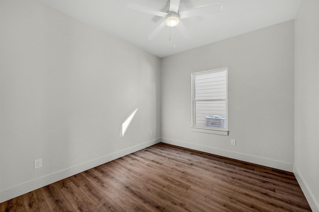 unfurnished room featuring dark wood-style floors, ceiling fan, and baseboards