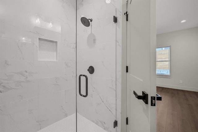 full bathroom featuring a shower stall, baseboards, and wood finished floors