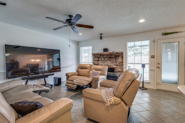 living area featuring a textured ceiling, plenty of natural light, a fireplace, and light tile patterned flooring