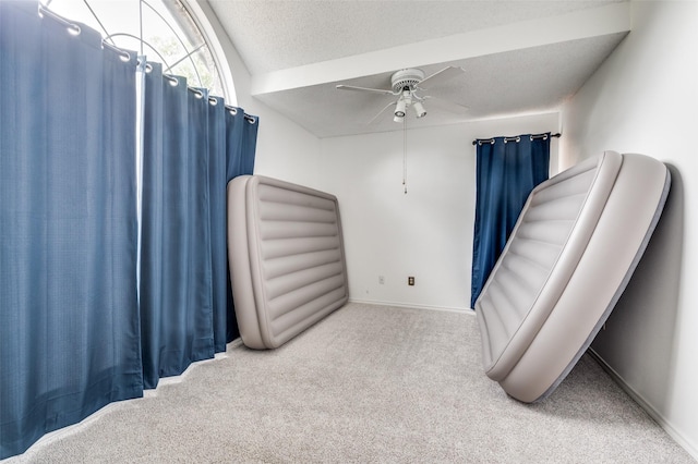 bedroom featuring light colored carpet, ceiling fan, a textured ceiling, and baseboards