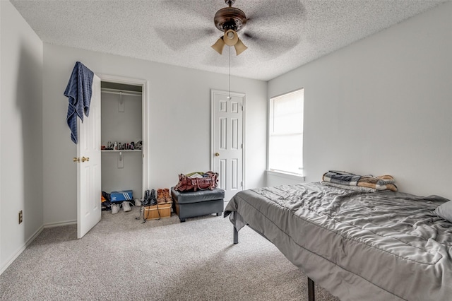 carpeted bedroom with ceiling fan, a textured ceiling, baseboards, and two closets