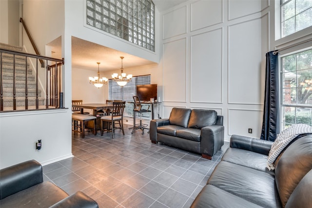 living area featuring a notable chandelier, a high ceiling, stairway, and a decorative wall